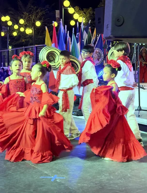 Las polleras rojas se abren en abanico durante el giro, con las banderas de los países latinos al fondo.