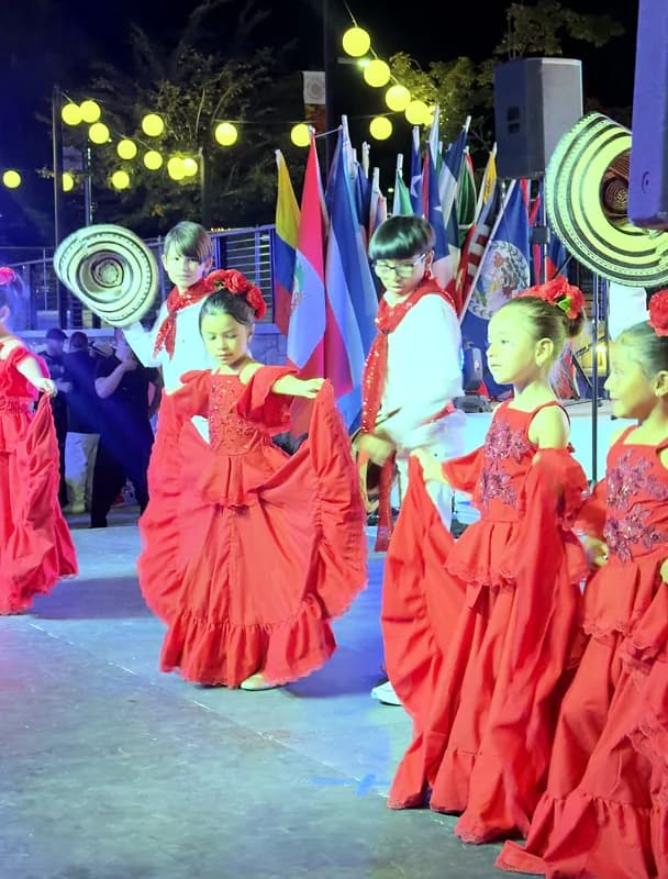 Una niña señala hacia adelante con la pollera en la mano mientras el grupo sigue la coreografía.