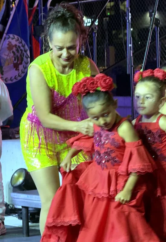 Tras bambalinas: una instructora ajusta el vestido de una bailarina antes de salir a escena.